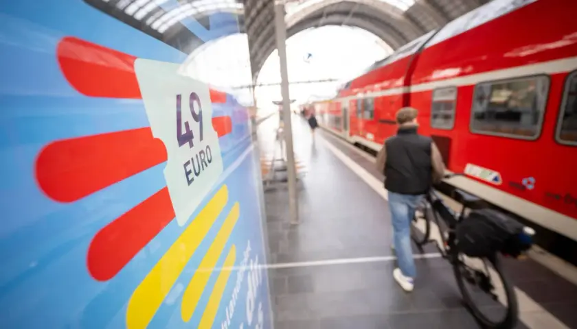 Mann mit Fahrrad am Bahnsteig, bereit für die Fahrt von Deutschland in die Niederlande. Das 49-Euro-Ticket ist im Fokus.