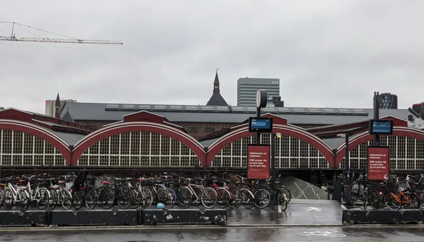 Fahrräder vor dem historischen Hauptbahnhof Kopenhagen. Ein Kran ragt in den grauen Himmel.