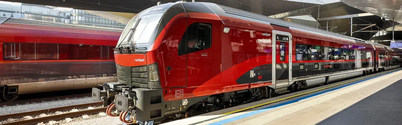 Roter Railjet Express Zug steht am Bahnsteig.