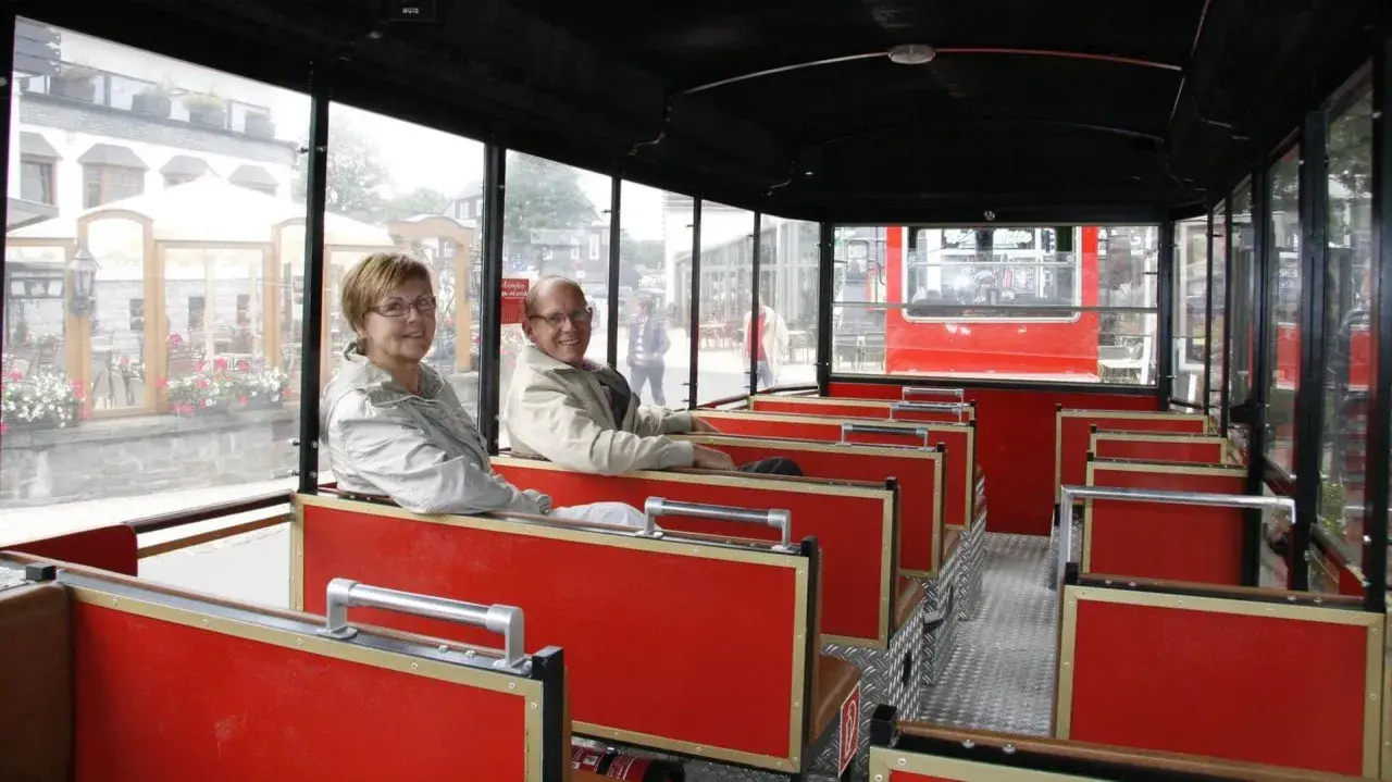 Ein älteres Paar genießt die Fahrt mit der Winterberg Bahn. Die roten Sitze und großen Fenster bieten einen tollen Ausblick.