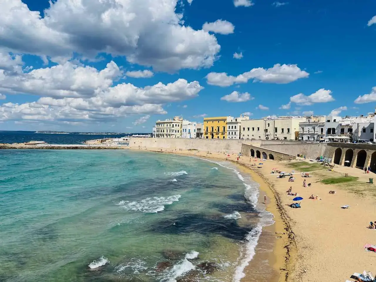 Sonne, Strand und Meer – ein gut mit Zug erreichbares Paradies. Türkisfarbenes Wasser trifft auf Sandstrand und weiße Häuser.