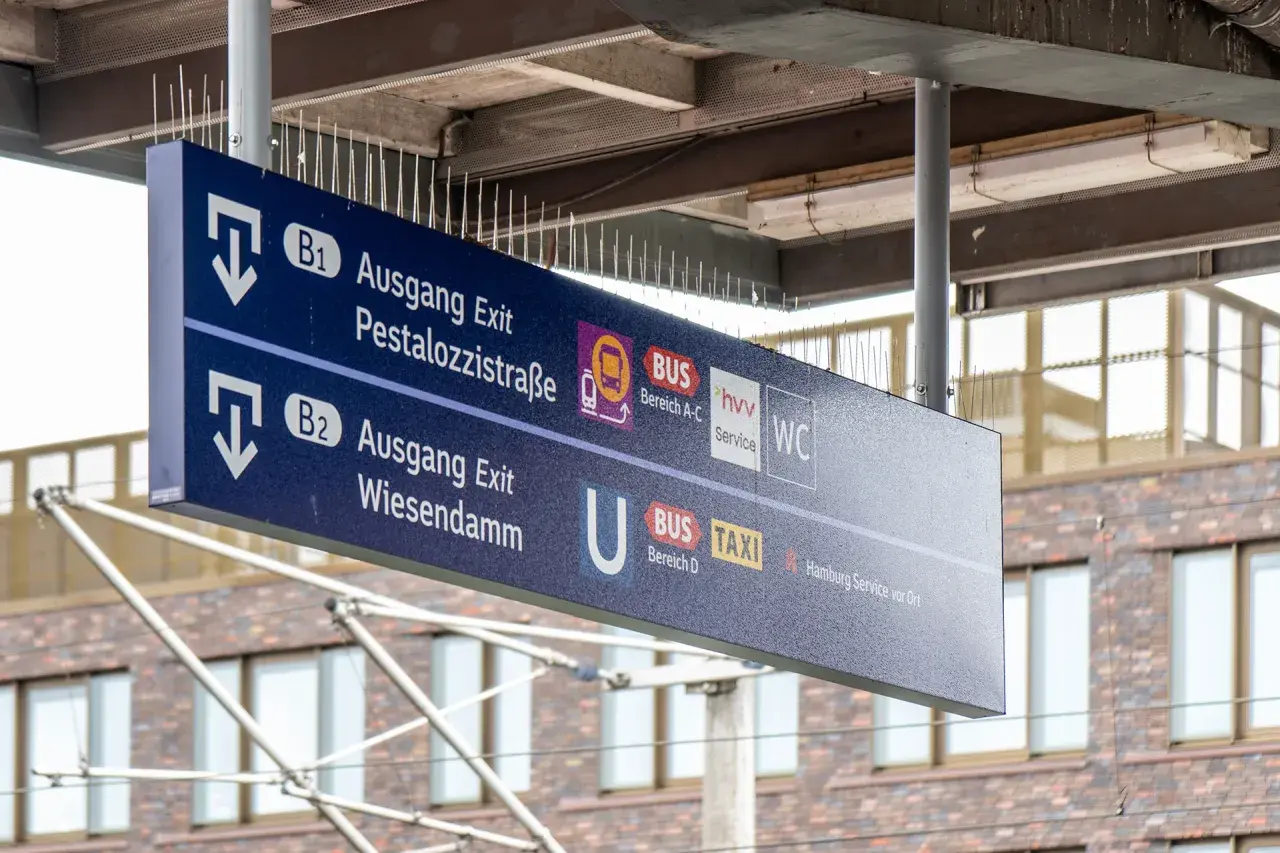 Wegweiser an einem Bahnsteig: Ausgang B1 zur Pestalozzistraße, B2 zum Wiesendamm, Bus, Taxi und WC.