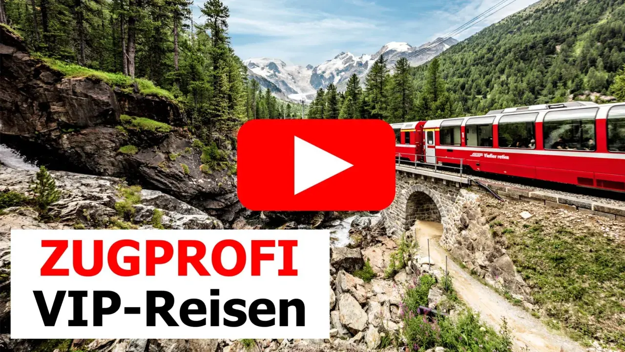 Roter Zug fährt über eine Steinbrücke durch eine Berglandschaft mit Wasserfall. Einer der besten landschaftlichen Zugfahrten.
