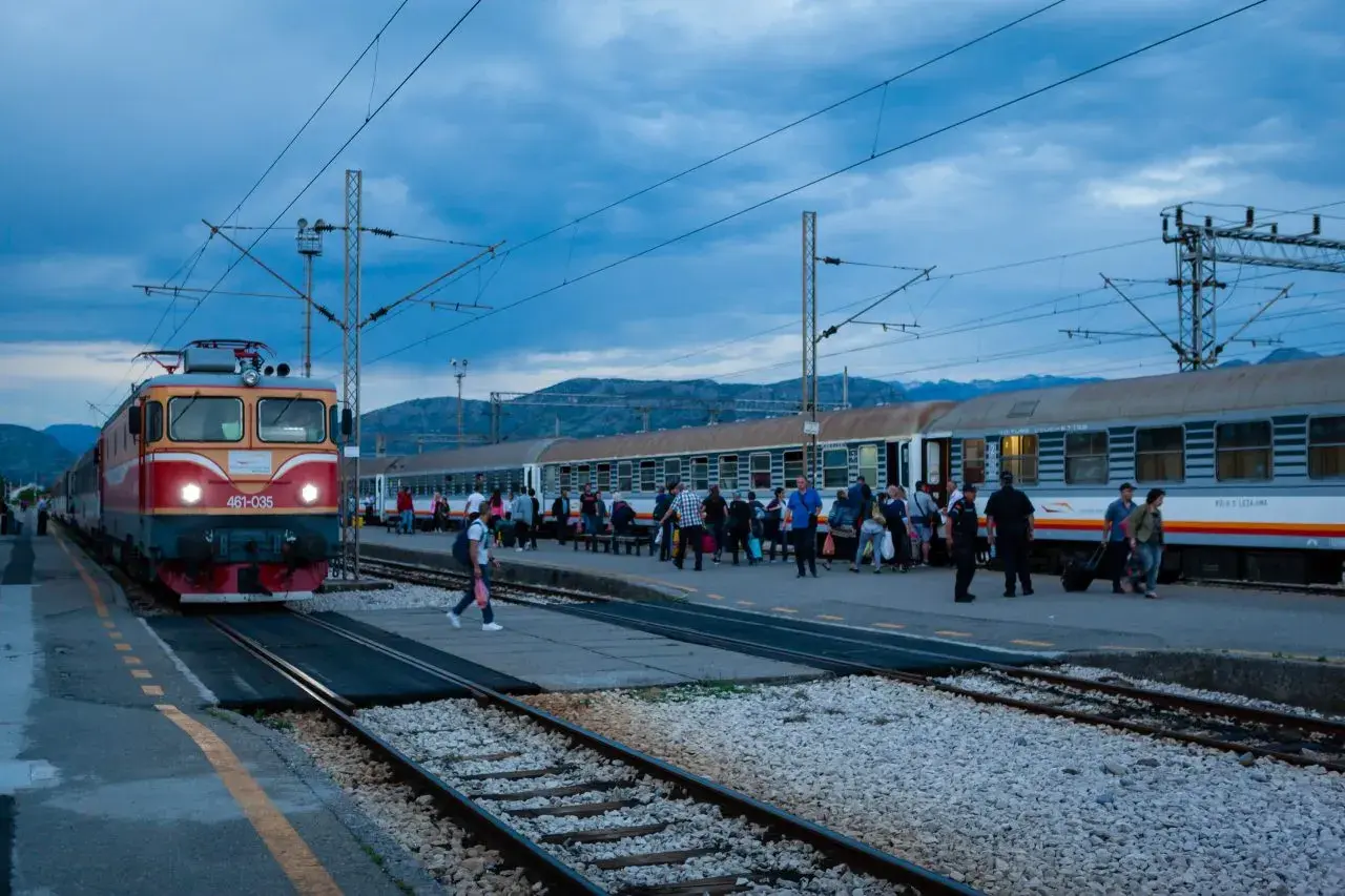Roter und gelber **montenegro train** am Bahnhof, Menschen steigen ein und aus.