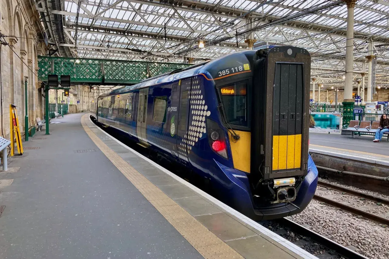 Ein moderner blauer Zug mit der Aufschrift "Edinburgh" steht bereit für die Abfahrt.