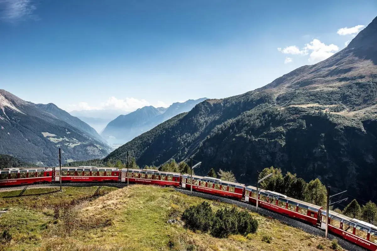 Der Bernina Express schlängelt sich **mit dem Zug durch die Schweiz** durch eine atemberaubende Berglandschaft.
