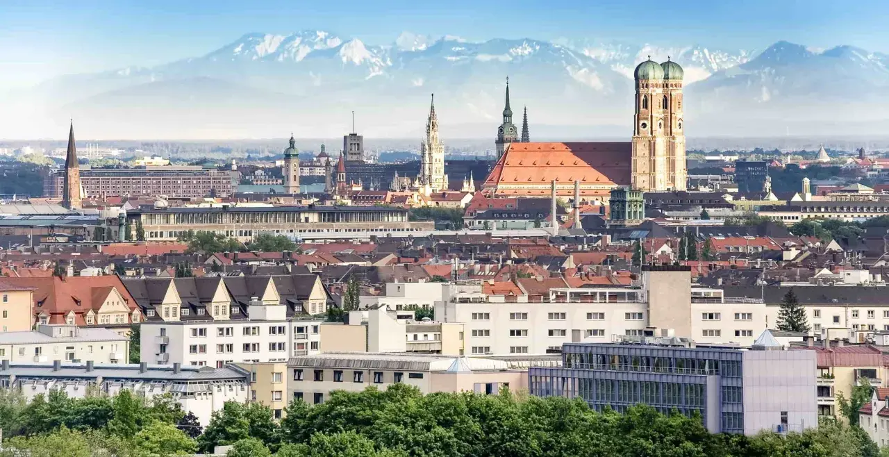 Blick auf München mit Alpen im Hintergrund. Die Zugfahrt von Köln nach München ist eine Reise durch Deutschland.
