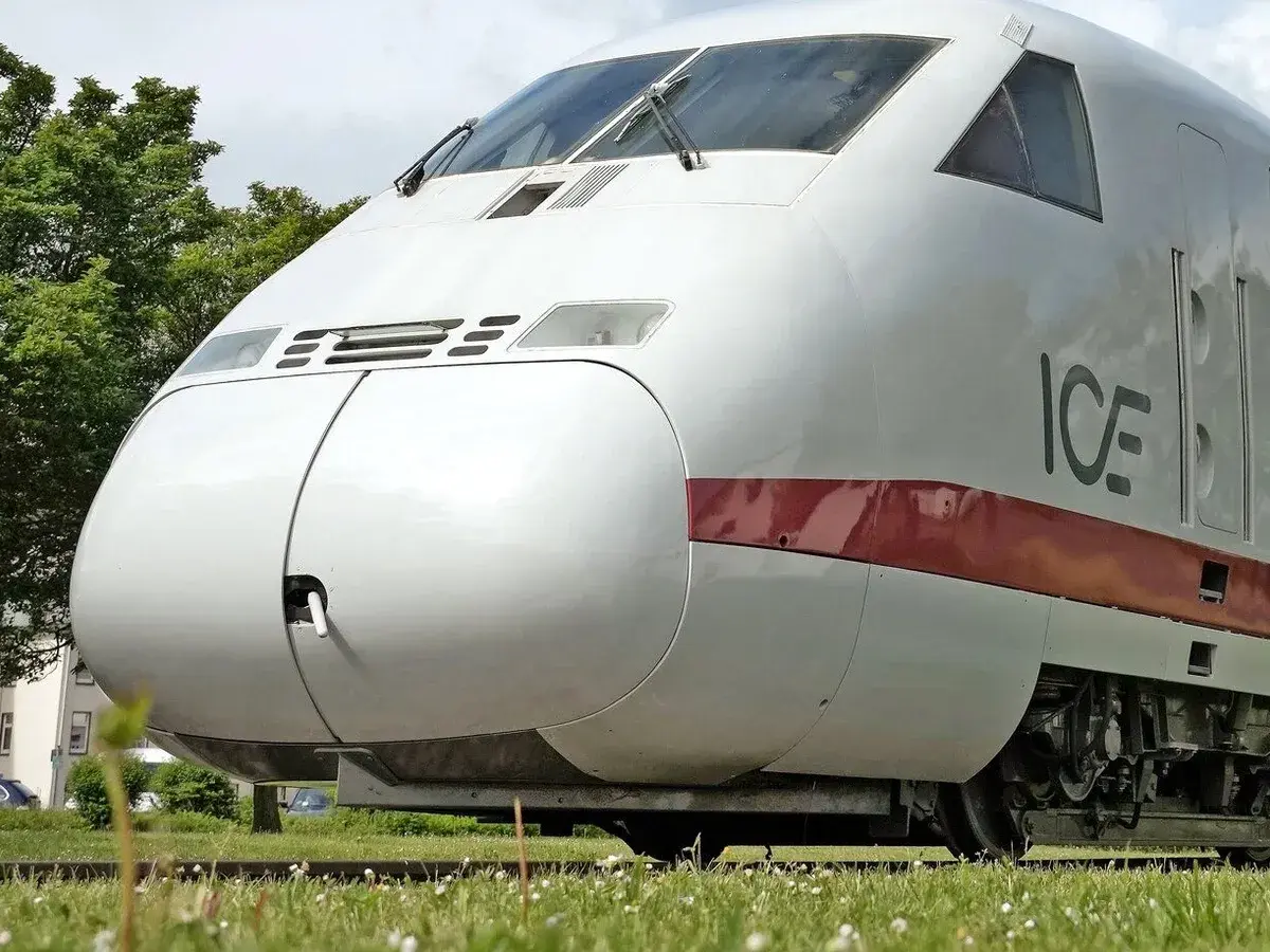 Der weiße ICE-Zug, ein deutscher Hochgeschwindigkeitszug, steht auf Gleisen im Gras.