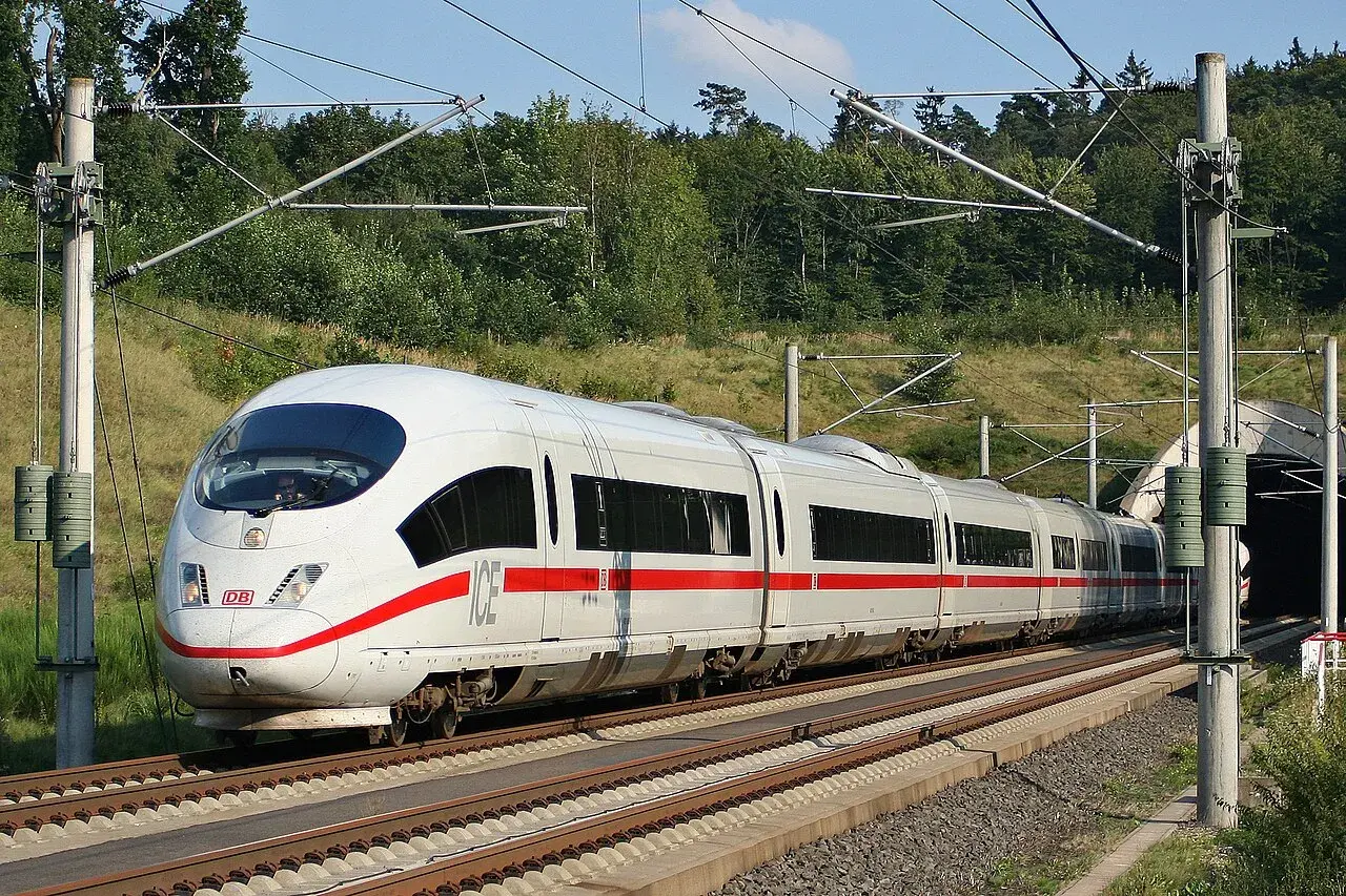Ein weißer ICE mit roten Streifen fährt auf den Gleisen Richtung Tunnel. Die Fahrt von Frankfurt nach Basel beginnt.