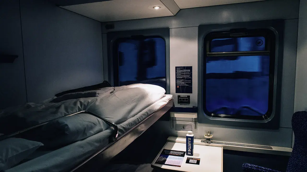 Gemütliches Schlafwagenabteil für die Reise von Hamburg nach Rom. Das Bett ist gemacht, bereit für eine erholsame Nacht.