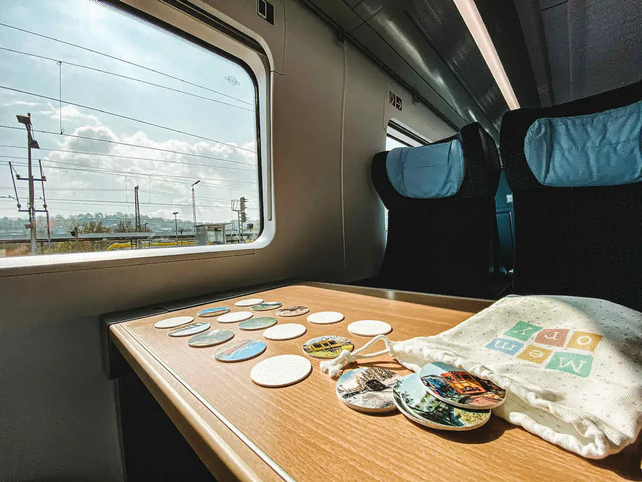 Blick aus dem Fenster eines **denmark train** mit vielen Untersetzern auf dem Tisch. Die Reise beginnt!