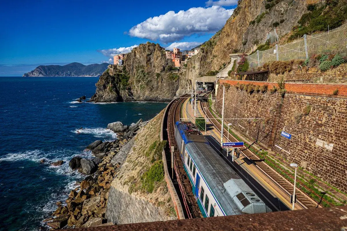 Zug fährt entlang der Küste von Manarola, ein malerischer Teil der Cinque Terre. Die Zugfahrt von Mailand hierher ist atemberaubend.