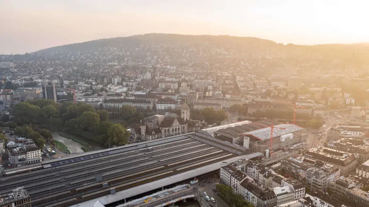Luftaufnahme des Hauptbahnhofs Zürich bei Sonnenuntergang. Die vielen Gleise deuten darauf hin, welcher Bahnhof die meisten Gleise hat.