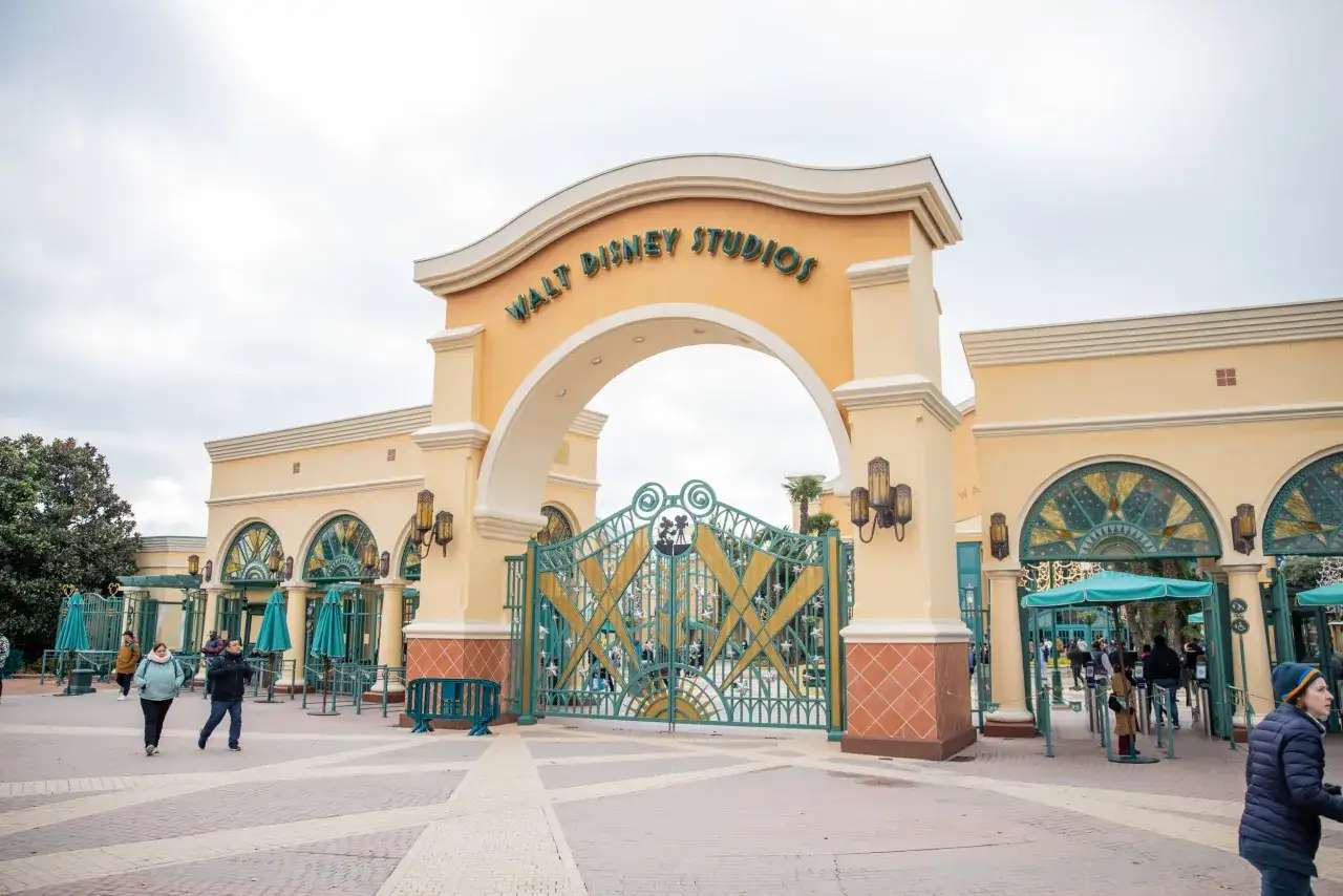 Eingang zum Walt Disney Studios Park in Disneyland Paris mit einer gro&szlig;en, verzierten gr&uuml;nen Pforte und Besuchern, die eintreten.