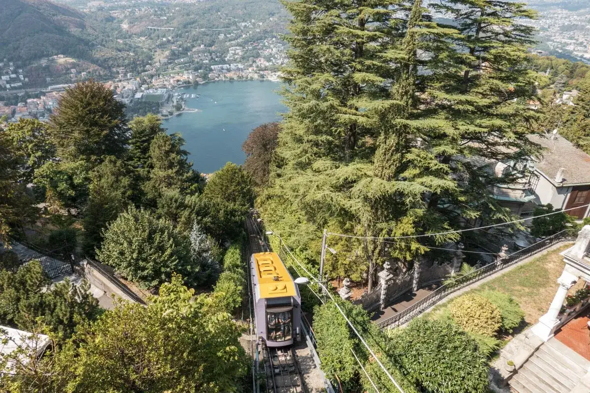 Gelbe Standseilbahn fährt bergauf, Blick auf Comer See und Stadt.