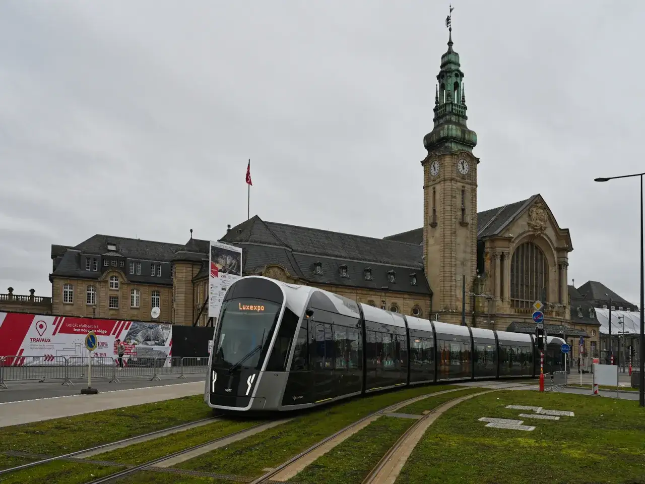 Moderner Zug fährt am historischen luxemburgischen Bahnhof vorbei.