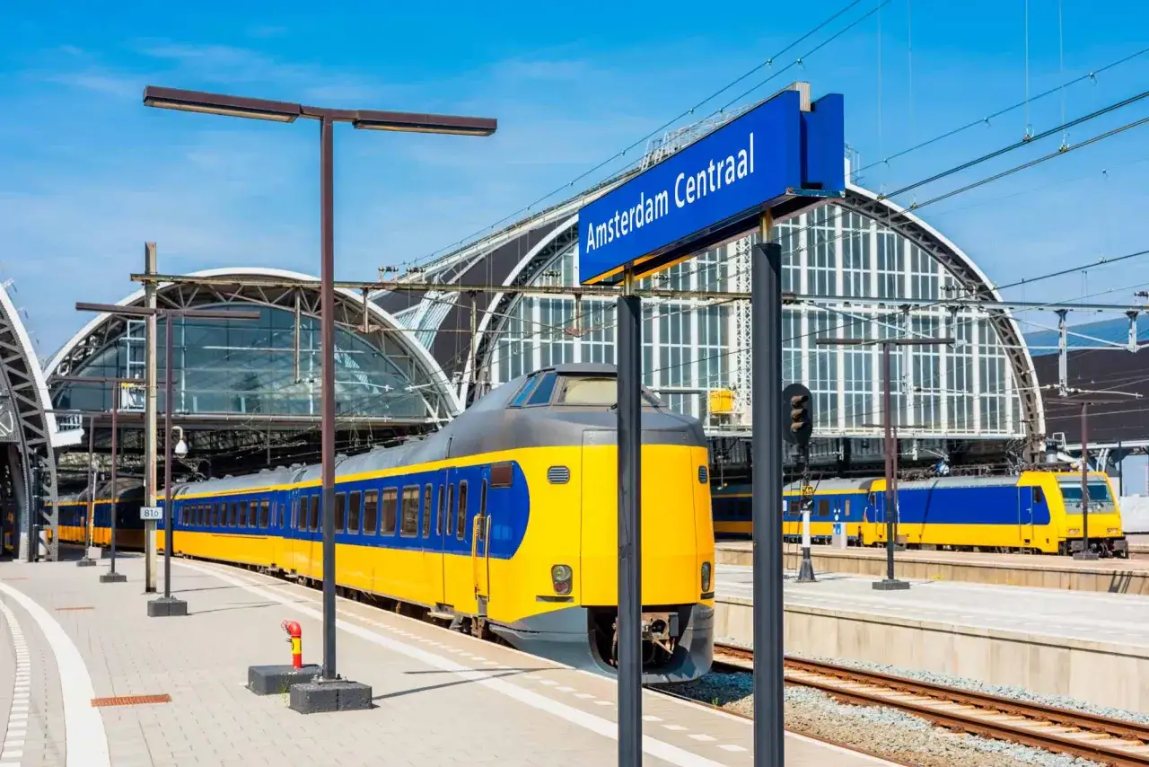 Ein gelb-blauer Zug steht am Bahnsteig von Amsterdam Centraal. Die Reise von Deutschland in die Niederlande beginnt hier.