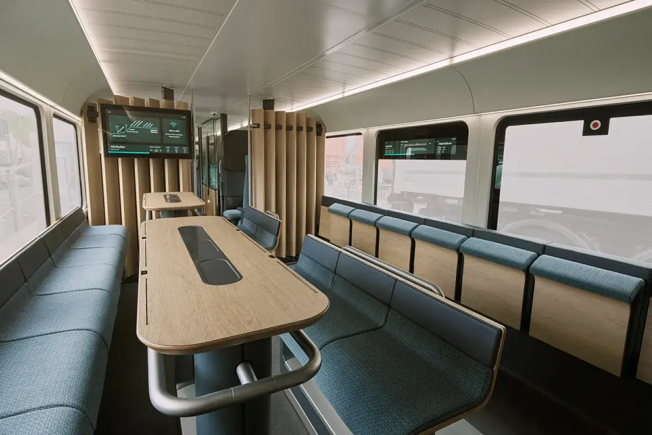 Moderne Sitze und Tische im Zugabteil laden zur entspannten reise im zug ein. Bildschirme zeigen Informationen.