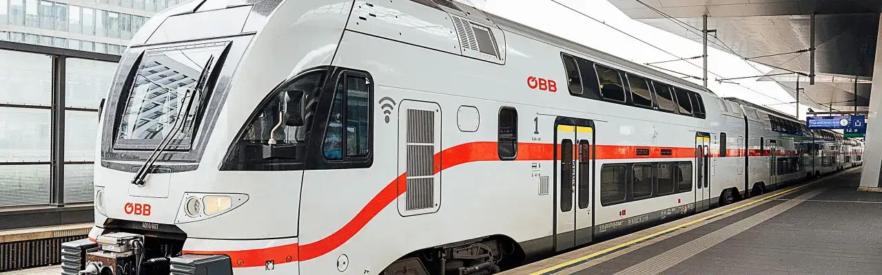 Moderner Eurocity Zug der ÖBB mit roten Streifen wartet am Bahnsteig.