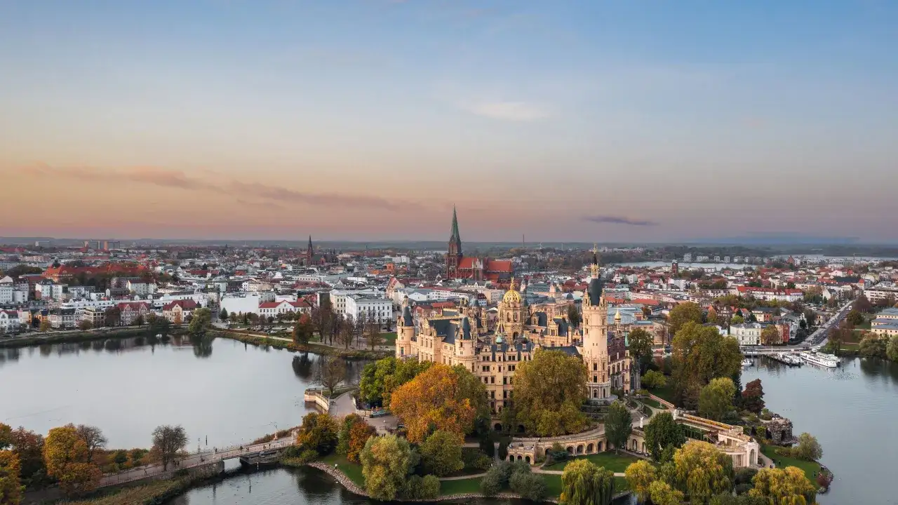 Schweriner Schloss auf einer Insel, umgeben von Wasser und einer Stadt mit Kircht&uuml;rmen. Ein sch&ouml;ner Ort, gut mit Zug erreichbar.