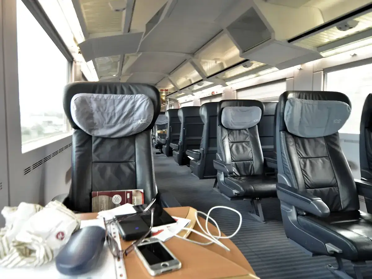 Komfortable Ledersitze im ICE first class. Auf dem Tisch liegen Handy, Brille und ein Buch.