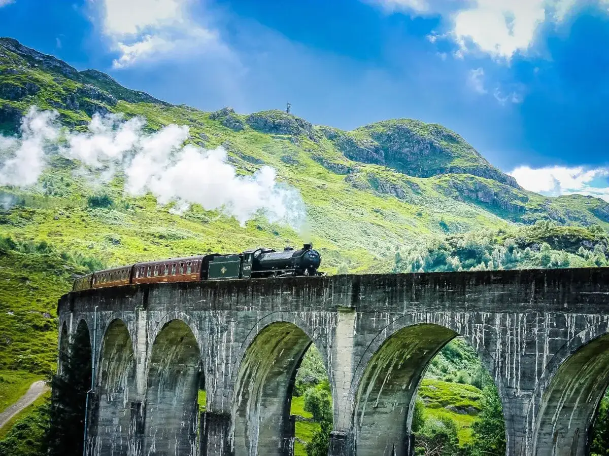 Dampflok f&auml;hrt &uuml;ber das Glenfinnan Viadukt, ein magischer Moment auf der Reise von Edinburgh in die Highlands.
