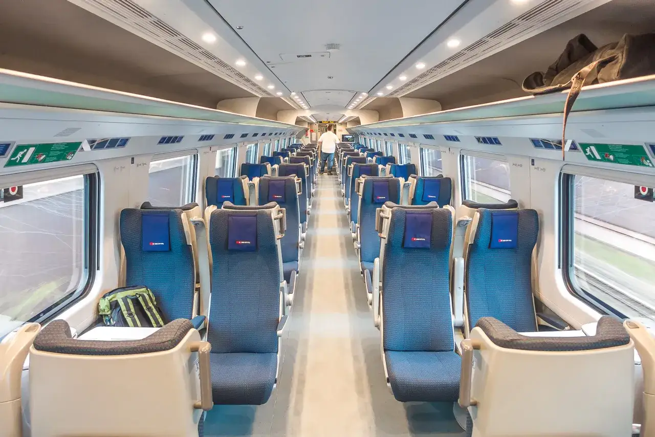 Innenraum eines modernen EC train Germany. Blaue Sitze mit Kopfstützen und Gepäckfächern über den Fenstern.