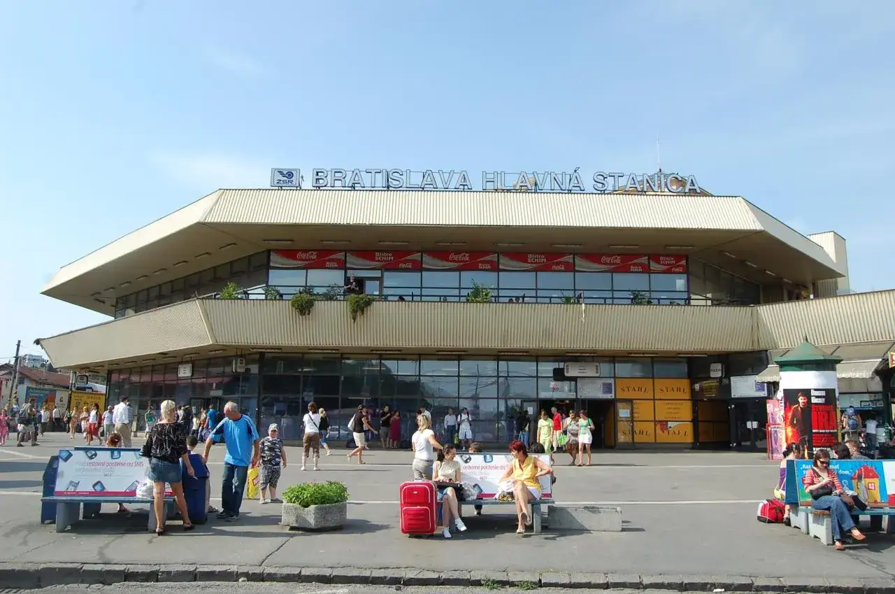 Menschen warten vor dem Bratislava Hlavn&aacute; Stanica, dem Hauptbahnhof von Bratislava, unter einem blauen Himmel.