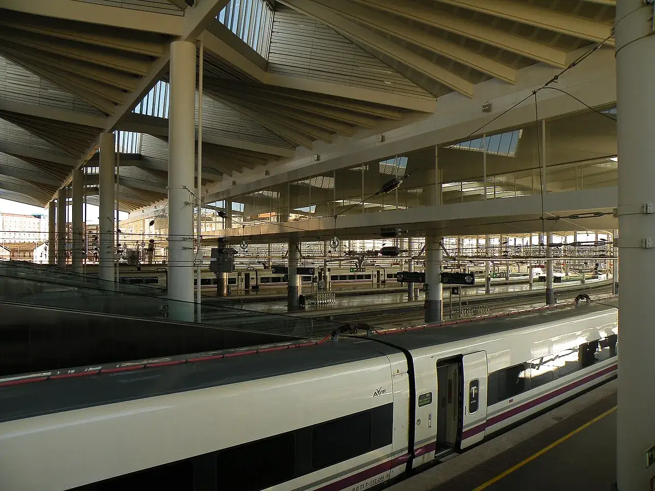 AVE Madrid: Moderne Bahnhofshalle mit Zügen auf mehreren Gleisen unter einem weitläufigen Dach.