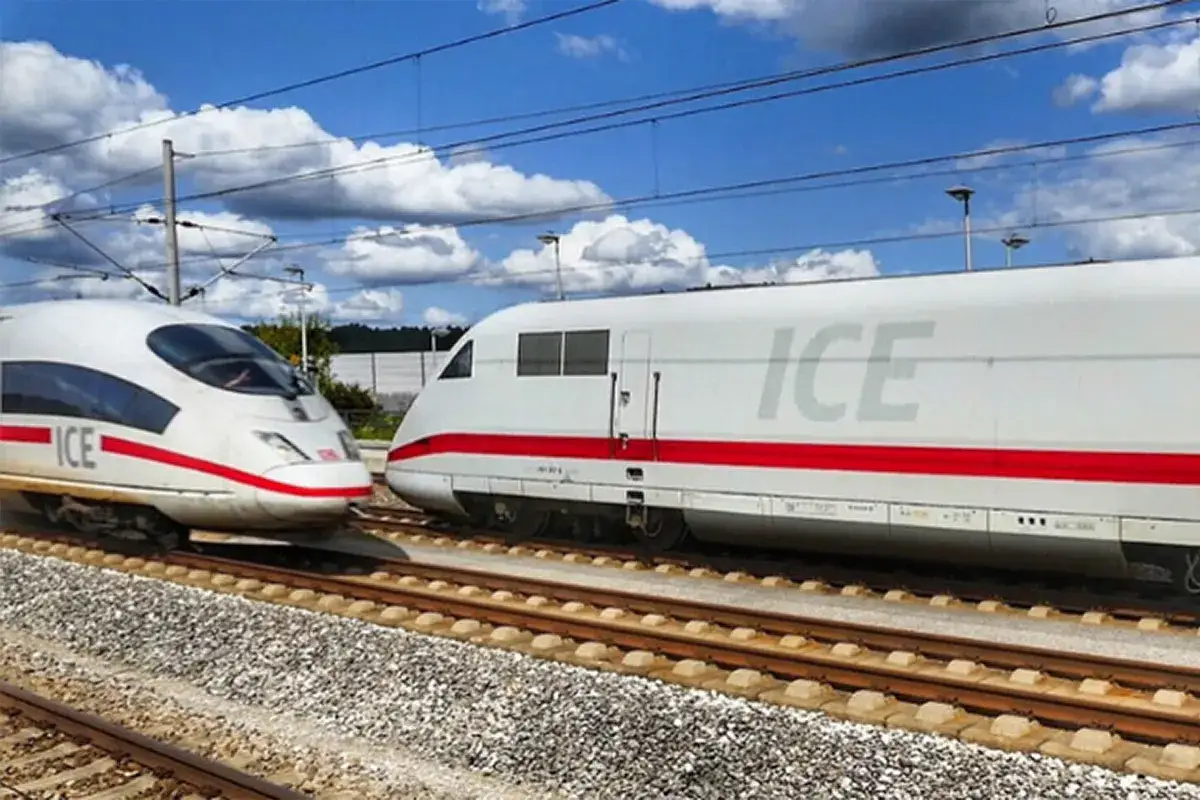 Zwei weiße ICE-Züge mit roten Streifen fahren auf parallelen Gleisen in Deutschland.