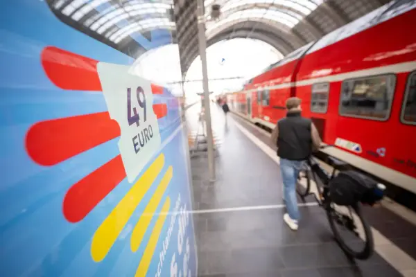 Mann mit Fahrrad am Bahnsteig, bereit für die Fahrt von Deutschland in die Niederlande. Das 49-Euro-Ticket ist im Fokus.